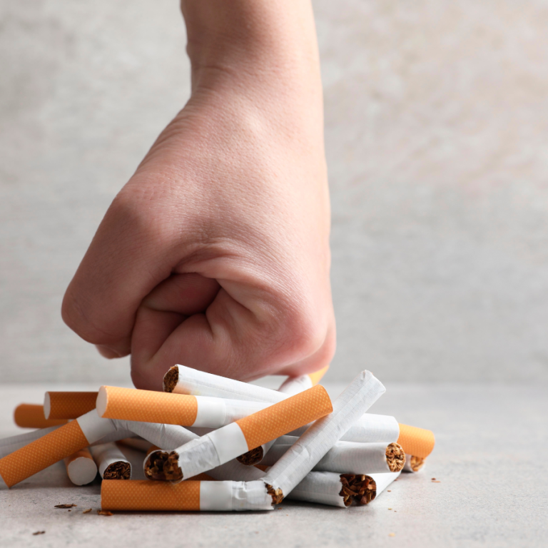 Hand crushing a pile of cigarettes